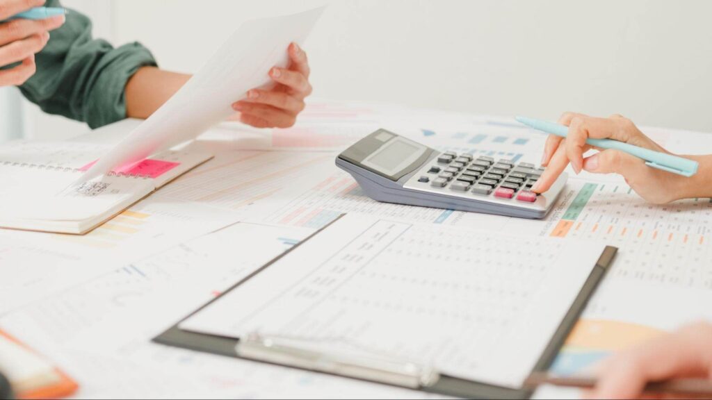 Business professionals reviewing financial documents and using a calculator during a tax planning session, highlighting GST HST compliance Canada and accurate financial reporting for Canadian businesses.