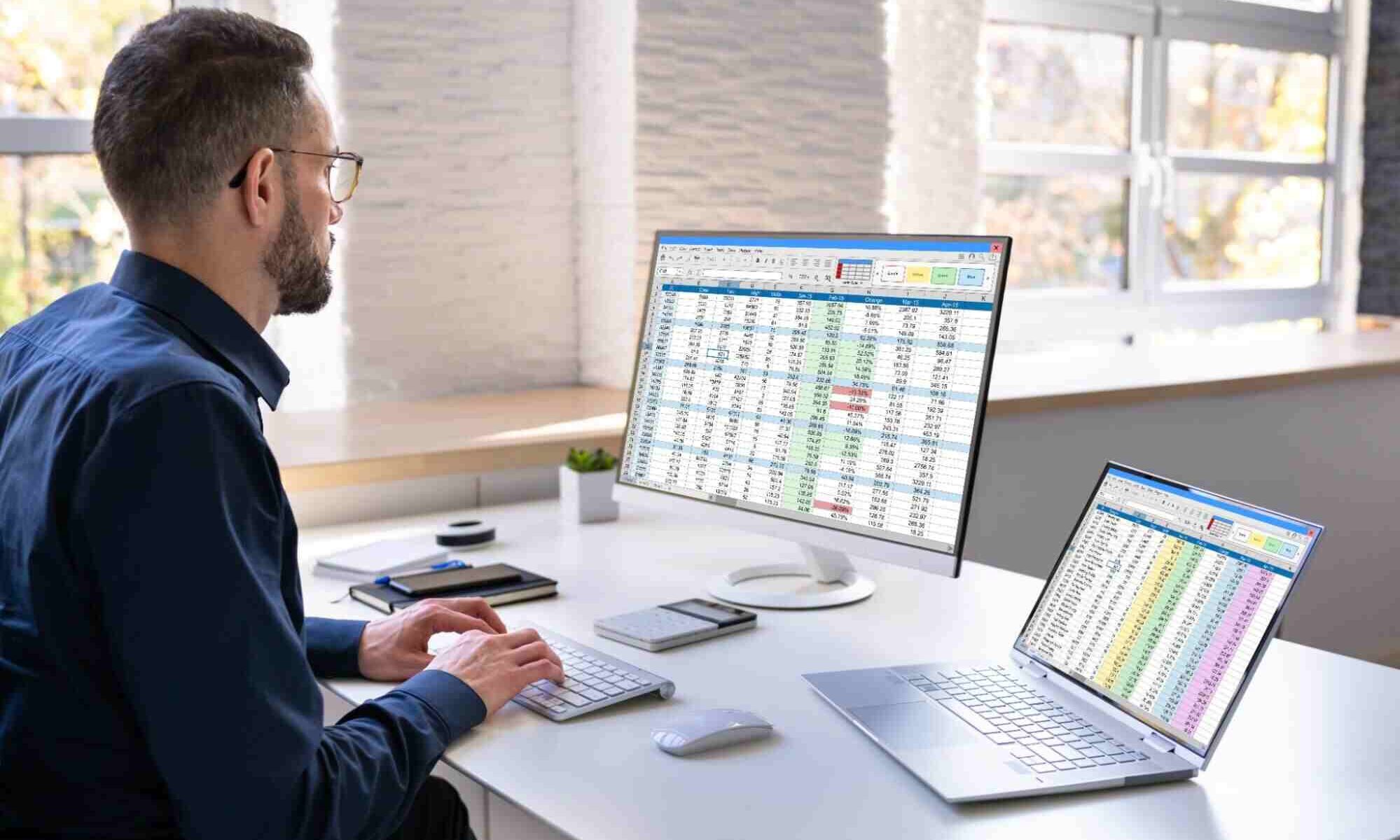 Corporate accounting Canada professional reviewing financial spreadsheets and business data on desktop and laptop computers.
